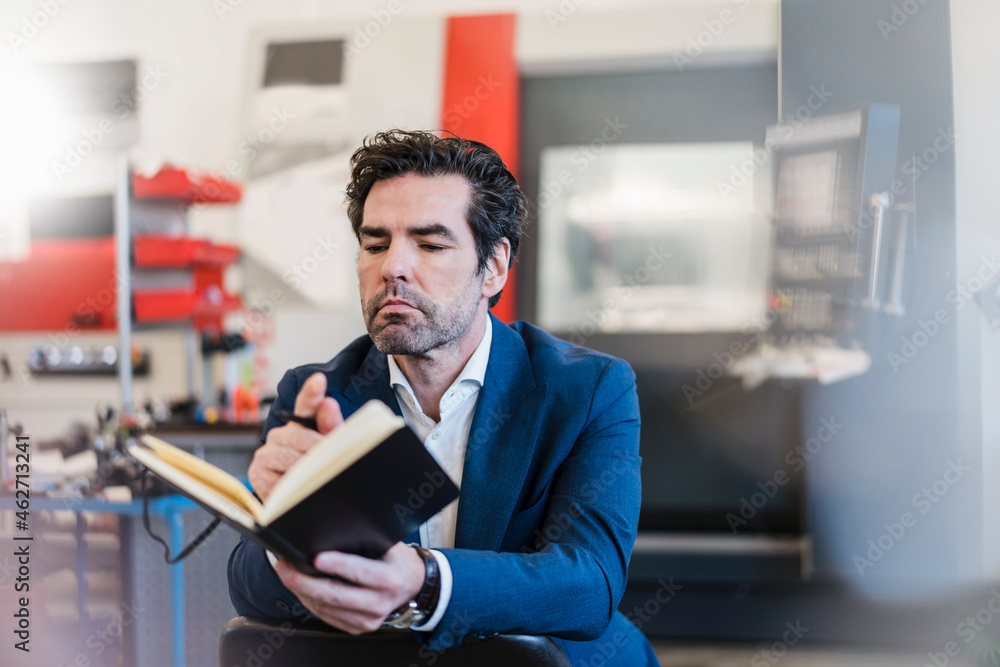 Businessman holding notebook in a factory Businessman holding notebook in a factory