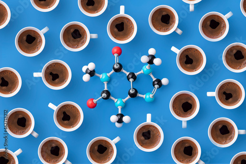 Directly above view of caffeine chemical formula with coffee cups over blue background