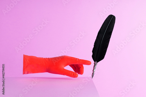 Quill pen pushed over the edge over pink background