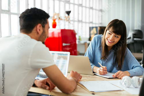 Smiling colleagues working at desk in office photo