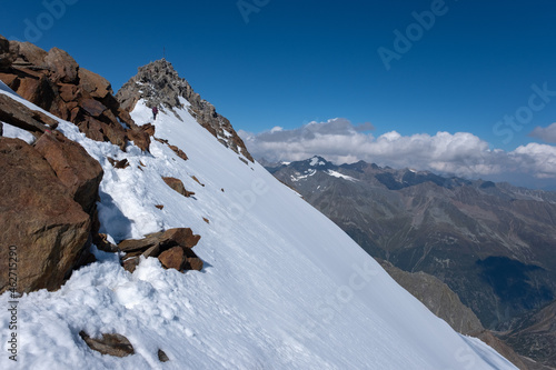 Climbers on the trail to the Wilder Freiger summit on the main Stubai mountain ridge, Austria. Sulzenau glacier. Border between Austria and Italy in Tyrol Alps. Summit cross on the top of the mount.