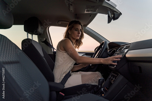 Blond woman driver choosing a radio channel in her car photo