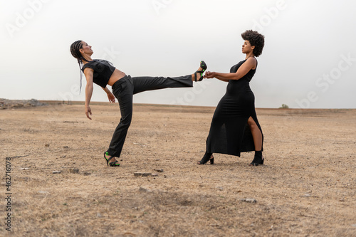 Young woman holding leg of other woman in bleak landscape photo