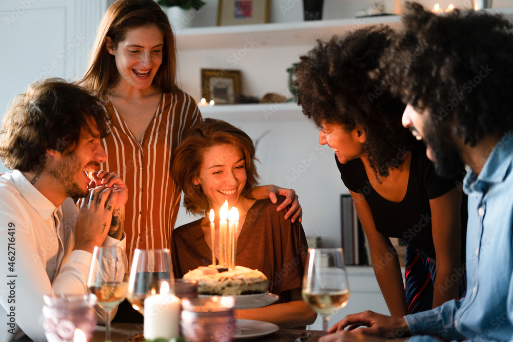 Friends surprising young woman with a birthday cake with burning candles Friends surprising young woman with a birthday cake with burning candles