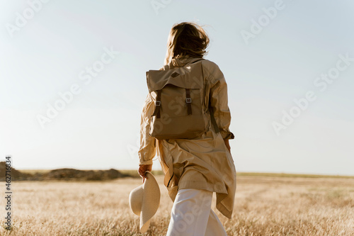 Rear view of female traveller with backpack on meadow photo
