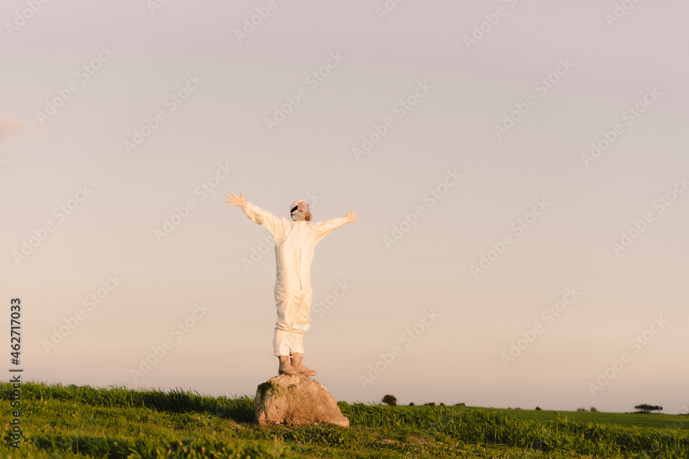 Man wearing protective suit and mask standing on a rock in the countryside Man wearing protective suit and mask standing on a rock in the countryside