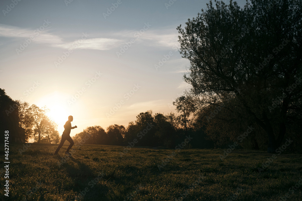 Silhouette of man jogging in a park at sunrise Silhouette of man jogging in a park at sunrise