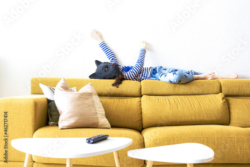 Girl lying on backrest of couch, imitating a cat, wearing mask photo
