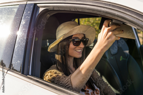 Smiling young woman sitting in a car taking selfie with cell phone photo