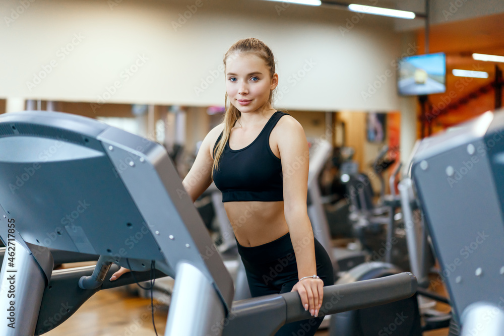 A young woman is engaged in fitness at the GYM. A woman on a treadmill. A young woman is engaged in fitness at the GYM. A woman on a treadmill.