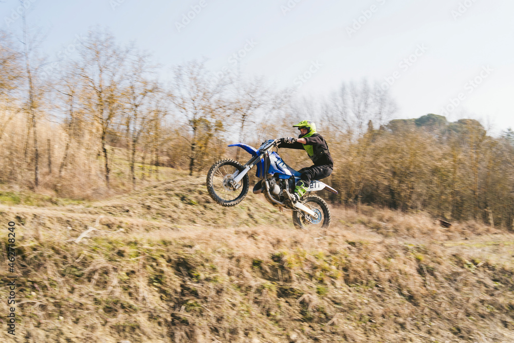 Motocross driver riding on circuit doing a wheelie Motocross driver riding on circuit doing a wheelie