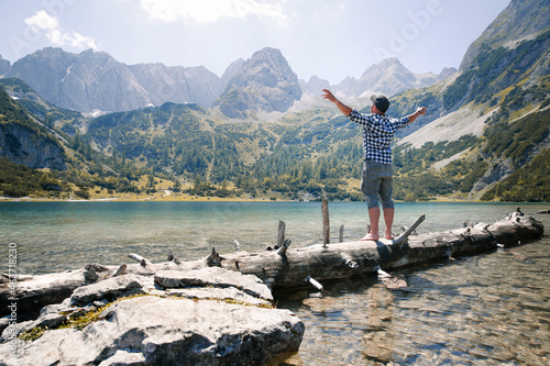 Austria, Tyrol, man standing on tree trunk at lake Seebensee photo