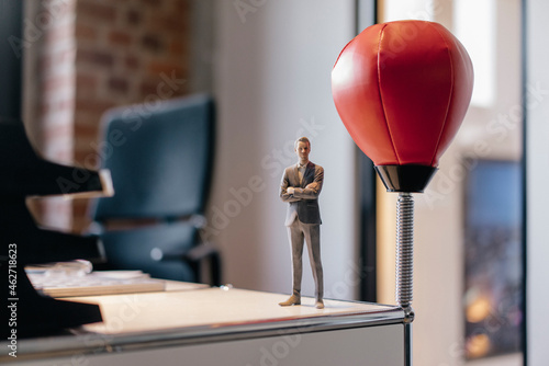 Businessman figurine standing on desk by punching ball photo