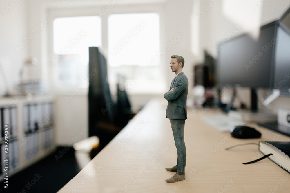 Businessman figurine standing on desk in modern office Businessman figurine standing on desk in modern office