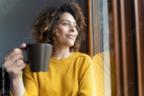 Woman sitting at window, taking a break, drinking coffee