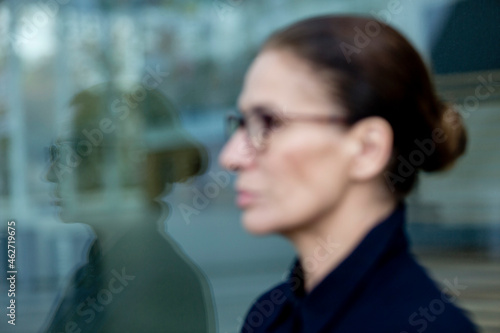 Portrait of mature woman mirrored in window glass photo