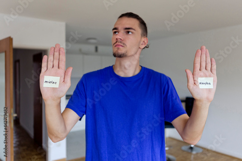 Young man in empty apartment with notes on the palms of his hands photo