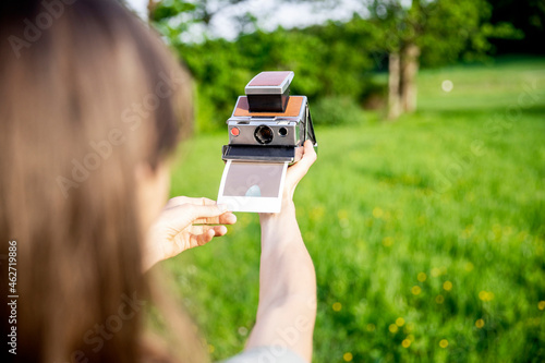 Close-up of woman taking instant photo on a meadow photo