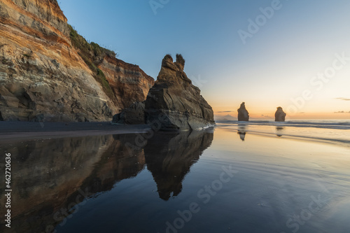 New Zealand, New Plymouth District, Tongaporutu, Three Sisters rock formation reflecting in wet shiny beach sand photo