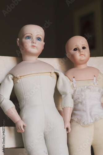 Obraz na plátne Pair of Vintage dolls on vintage chair - doll parts