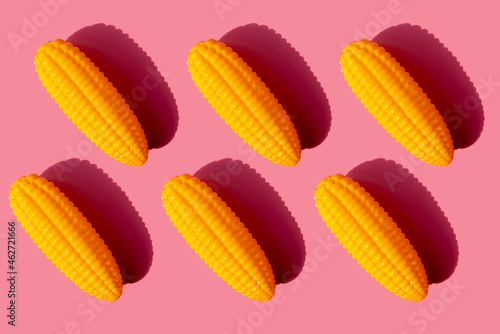 Studio shot of six plastic corn cobs against pink background photo