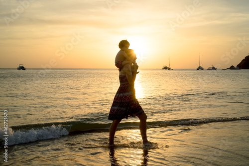 Thailand, Koh Lanta, silhouette of mother with baby girl on her shoulders at seashore during sunset photo
