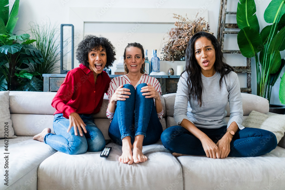 Three excited women on couch at home watching Tv Three excited women on couch at home watching Tv
