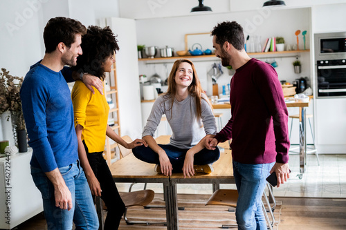 Four happy friends at dining table at home photo