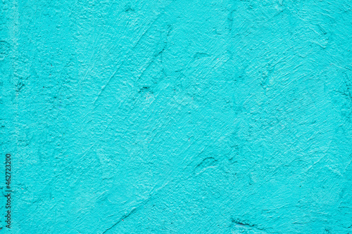 Rough plaster wall, bright turquoise color, scratched surface, background