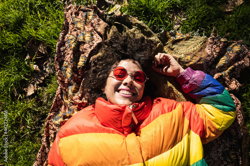 Smiling woman wearing jacket lying down while resting at park