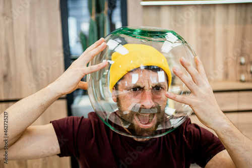 Frustrated businessman screaming while wearing fishbowl in modern office