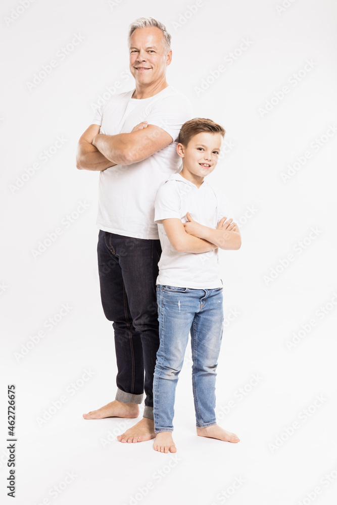 Father and son with arms crossed posing while standing against white background Father and son with arms crossed posing while standing against white background
