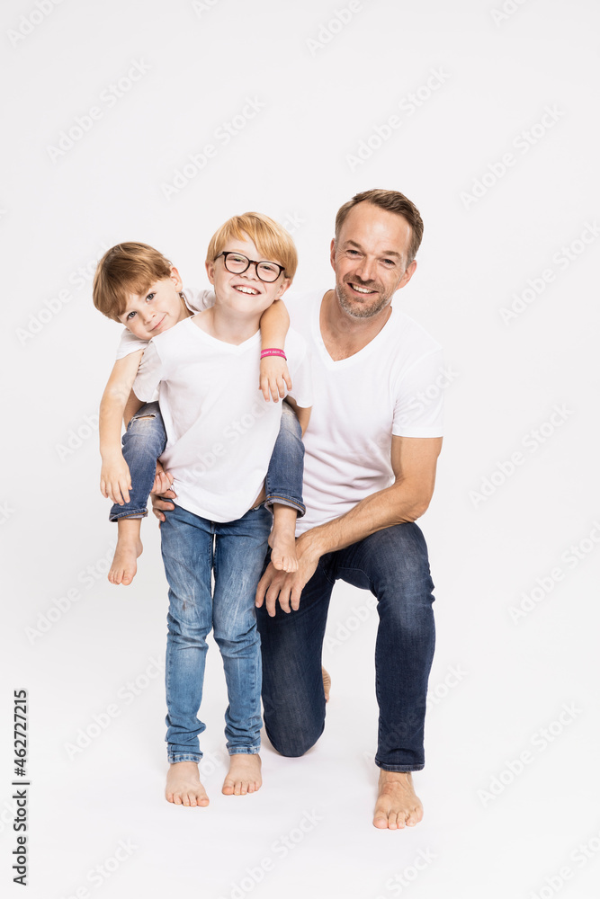 Boy piggybacking brother while standing by father against white background Boy piggybacking brother while standing by father against white background