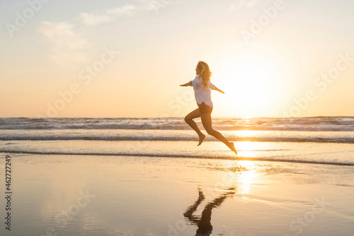 Happy woman with arms outstretched jumping against sea photo