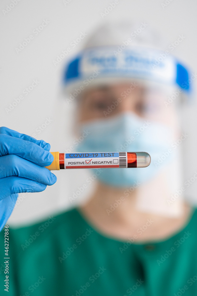 Woman in protective wear holding positive covid-19 test Woman in protective wear holding positive covid-19 test