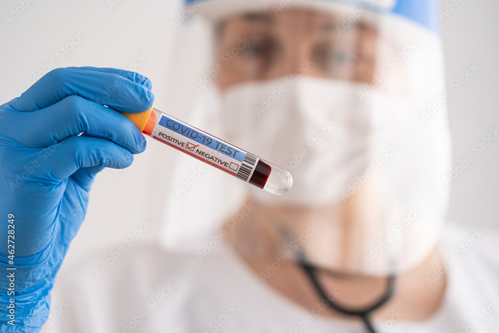 Woman in protective wear holding positive covid-19 test Woman in protective wear holding positive covid-19 test