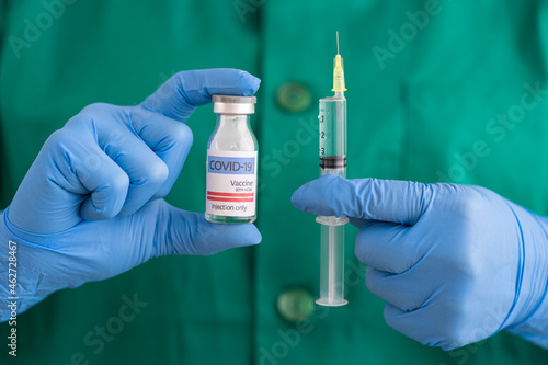Woman in protective wear holding covid-19 vaccine and syringe photo
