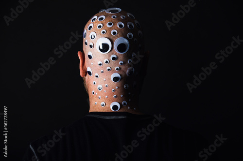 Bald man with head covered in googly eyes
