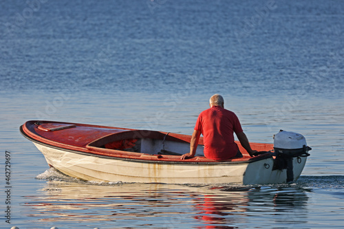 Fototapeta Fisherman on a motorboat goes to sea