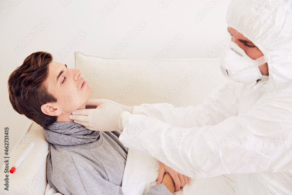 Doctor wearing protective suit examining patient resting on sofa at home Doctor wearing protective suit examining patient resting on sofa at home