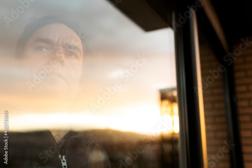 Portrait of serious mature man looking out of window at sunset