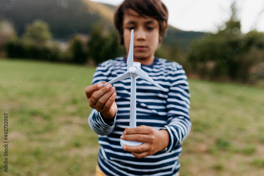 Boy playing with wind turbine while standing at backyard Boy playing with wind turbine while standing at backyard