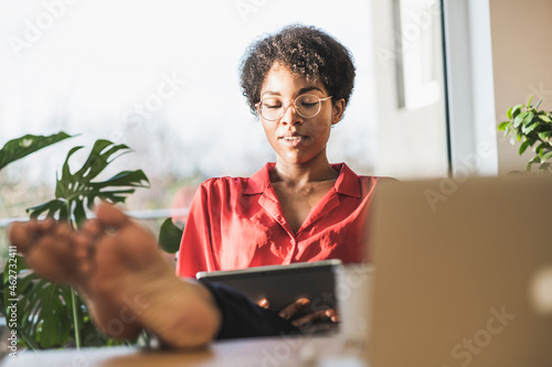 Woman with bare feet on desk using digital tablet photo