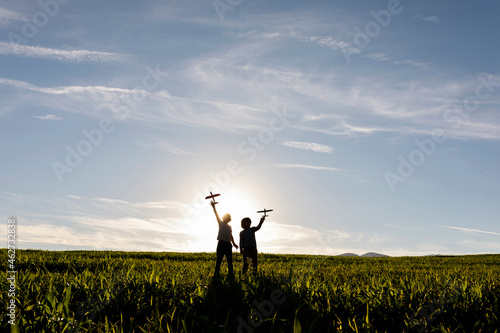 Silhouette of boys holding toy while standing against clear sky