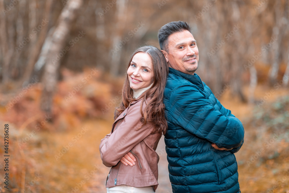 Couple standing back to back with arms crossed in park during autumn Couple standing back to back with arms crossed in park during autumn