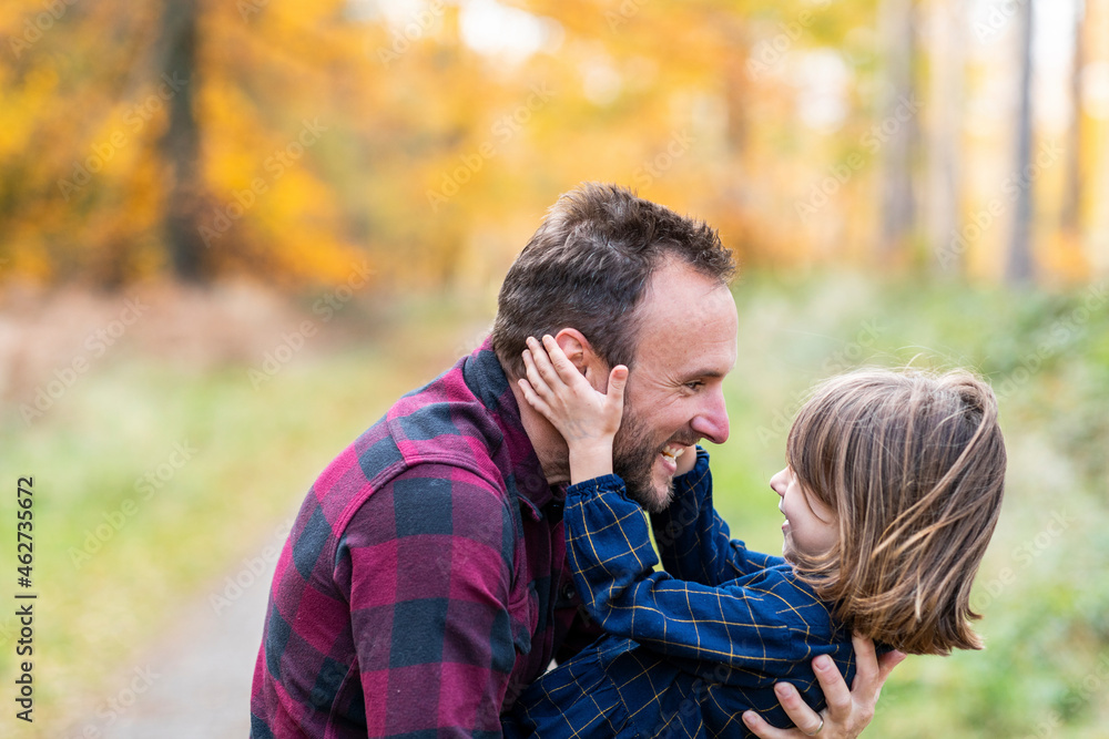 Smiling father carrying daughter while playing in forest Smiling father carrying daughter while playing in forest