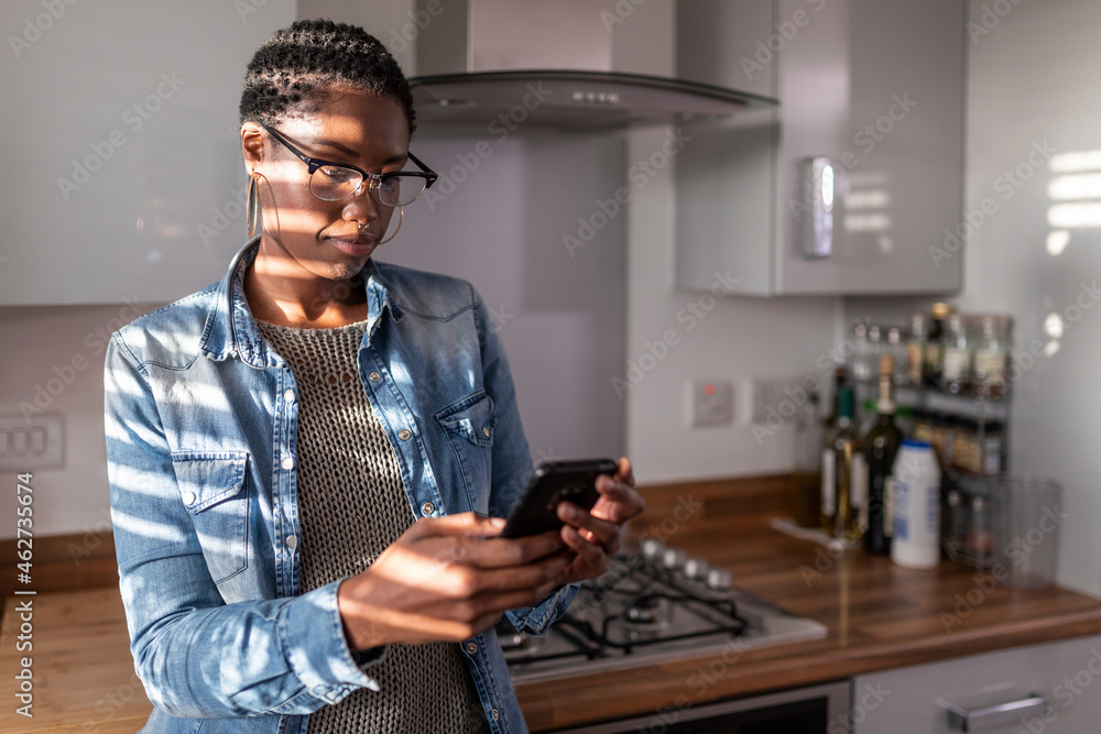 Woman looking at smart phone in kitchen Woman looking at smart phone in kitchen