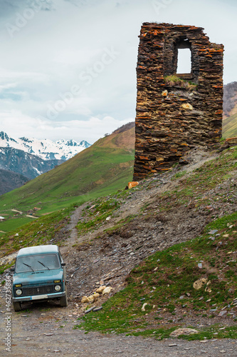 Georgia, Svaneti, Ushguli, Old car parked in front of old medieval brick tower photo