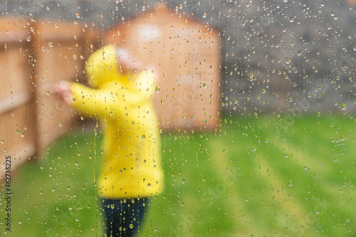 Woman enjoying rain with arms outstretched while standing in back yard during rainy season photo