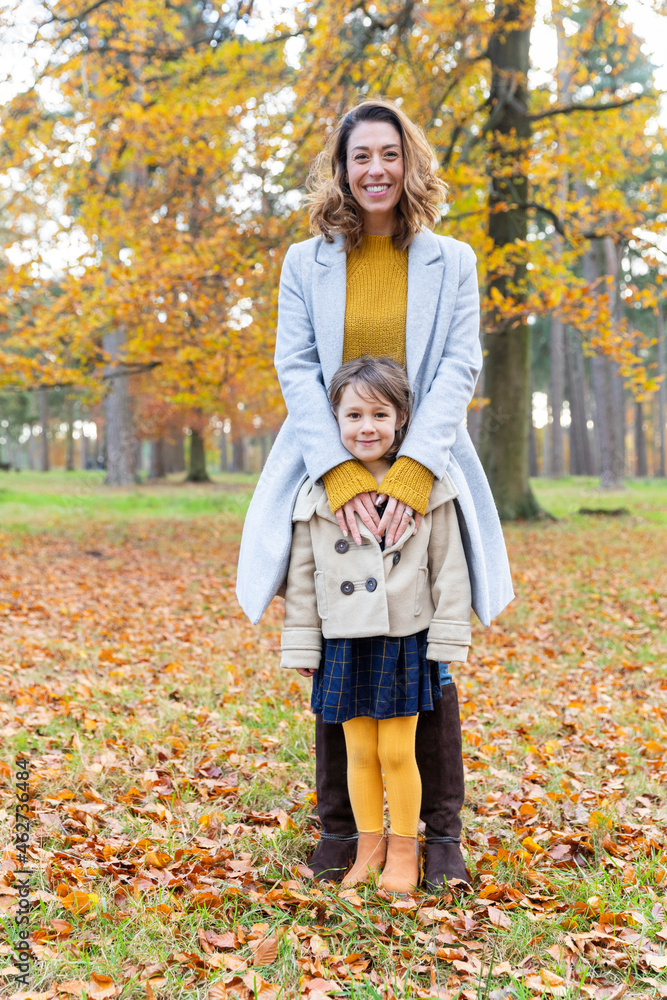 Smiling mother standing with daughter in forest Smiling mother standing with daughter in forest